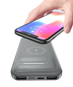 En hånd holder en smartphone over en hvid Powerbank Wireless Pro 10.000mAh med flere porte.