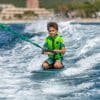 Dreng wakeboarder på havet iført en grøn dragt.