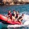 Fire personer på en rød bananbåd på havet