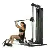 Kvinde sidder ved multigym og træner.