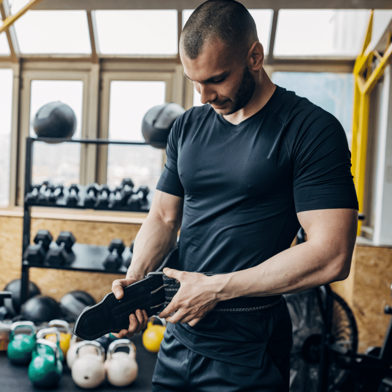 Mand står i fitnesscenter med en vægtløftningsbælte