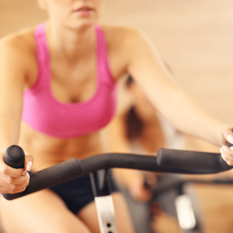 Kvinde træner på motionscykel i fitnesscenter