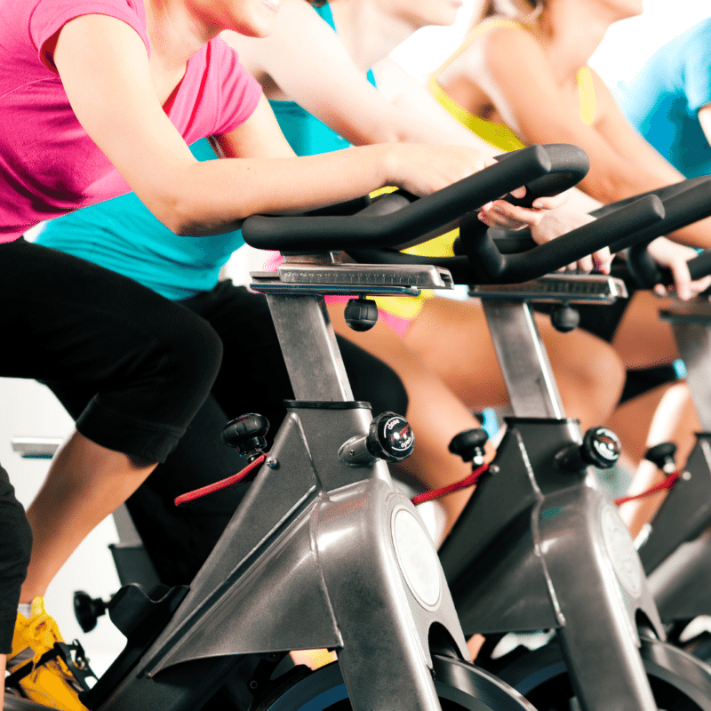 Tre personer på motionscykler i et fitnesscenter