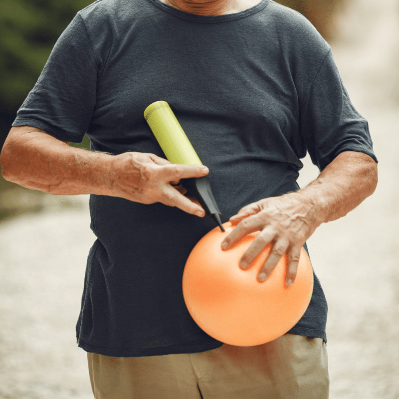 Mand pumper orange ballon op med håndpumpe