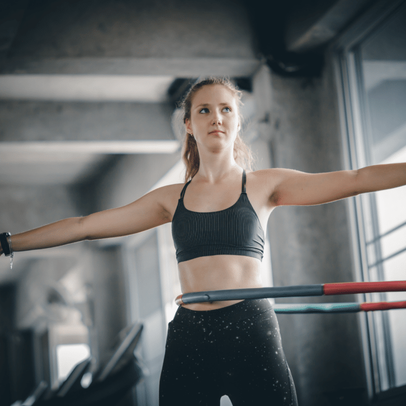 Kvinde træner med hulahopring i fitnesscenter.