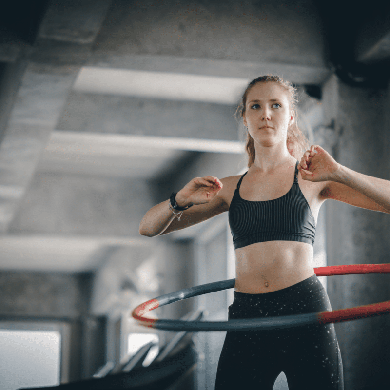 Kvinde svinger hula hoop i fitnesscenter