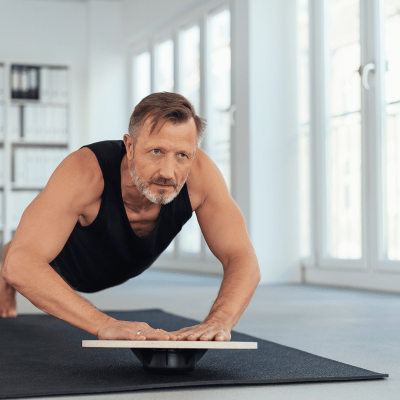 Mand laver øvelser på balancebræt.