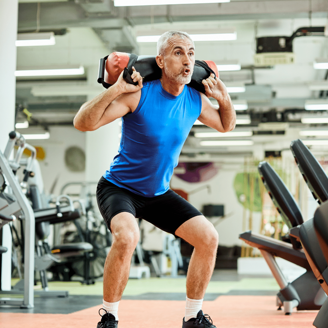 Mand laver squats med vægt på skuldrene i et fitnesscenter.