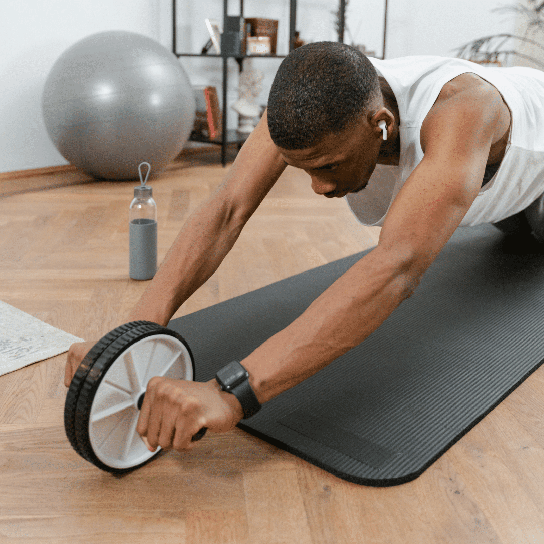 Mand træner med ab wheel på yogamåtte.