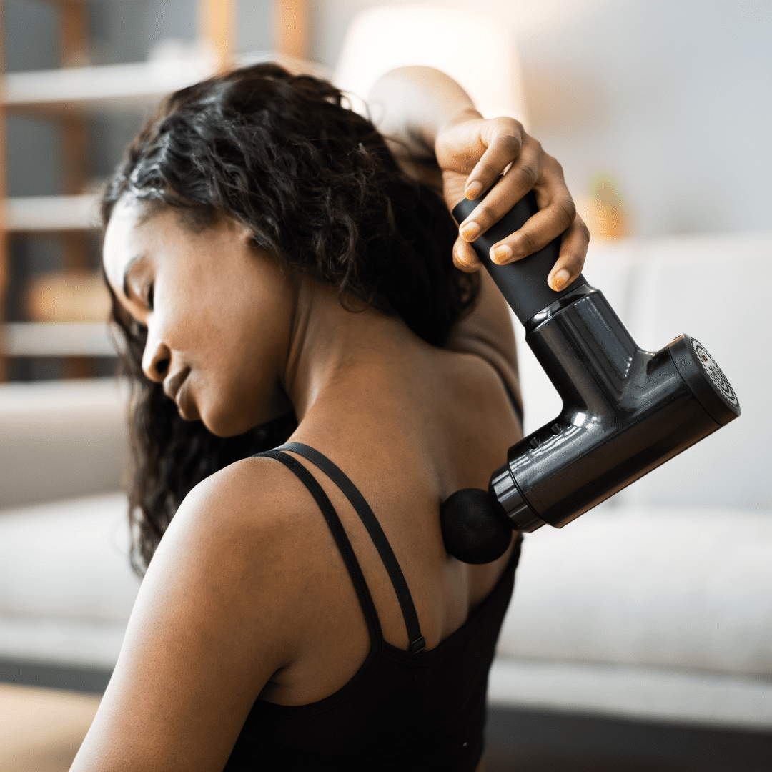 Kvinde anvender en massagepistol på ryggen.