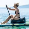 Kvinde sidder på et paddleboard med oppustelig sæde på vandet.