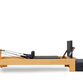 Pilates reformer i træ med sorte polstrede dele.