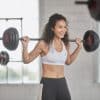 Kvinde i fitnesscenter løfter vægtstang