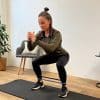 Person laver squat med elastik omkring benene.