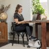 Kvinde ved skrivebord med pedaltræner og bærbar computer