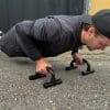 Mand laver push-ups med håndtag udendørs