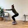 Kvinde i grønt træningstøj balancerer på en balancebræt.