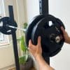 Person justerer vægtskiver på en vægtstang.