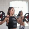 Kvinde løfter vægtstang under træning i fitnesscenter.