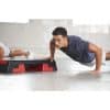 Mand laver push-ups ved siden af en stepbænk i et fitnesscenter.