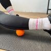 Person bruger bold til massage af benet.