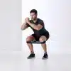 Mand laver squat med et modstandsbånd om benene.