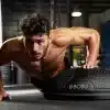 Mand laver armbøjninger på en BOSU bold i et fitnesscenter.