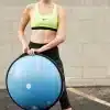 Kvinde i træningstøj holder en blå BOSU bold.