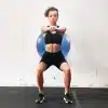 Kvinde der udfører squat med fitnessbold på ryggen.