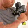 Mand bruger massagepistol på sin skulder.