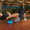 Kvinde bruger en blå foam roller i et træningscenter.