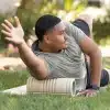 Mand bruger foam roller på græsset.