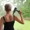 Kvinde anvender massagepistol på ryggen.
