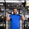 Mand i blåt træningstøj holder to TRX-vægte.