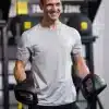 Mand i gråt tøj holder håndvægte i et fitnesscenter
