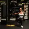 Kvinde laver øvelse med TRX-stropper i et fitnesscenter.