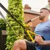 Mand udfører øvelse med TRX i baghaven.