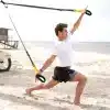 Mand udfører TRX-øvelse på stranden.