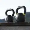 To kettlebells på en træoverflade med bjerge i baggrunden.