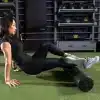 Kvinde laver foam rolling på grøn måtte i fitnesscenter.