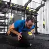 Mand laver en øvelse med en medicinbold i et fitnesscenter.