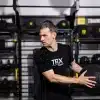 Mand i sort TRX-t-shirt holder en medicinbold.