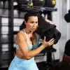 Kvinde løfter en sandpose i et fitnesscenter.