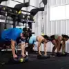 Gruppe laver øvelser med træningsudstyr i fitnesscenter.