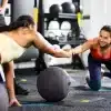 To kvinder laver øvelser med medicinbold i et fitnesscenter.