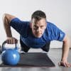 Mand udfører øvelse med kettlebell på en yogamåtte