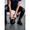 Person i træningstøj løfter en kettlebell