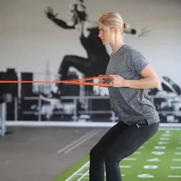 Kvinde træner med elastikbånd i fitnesscenter.