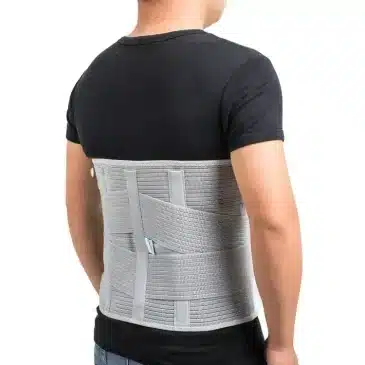 En person iført en grå rygkorset, der dækker lænden og ryggen. Personen har en sort T-shirt på.